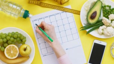 Sağlıklı gıda, diyet, üst görünüm, sarı arka plan kavramı bir fitness takvimi tutmak