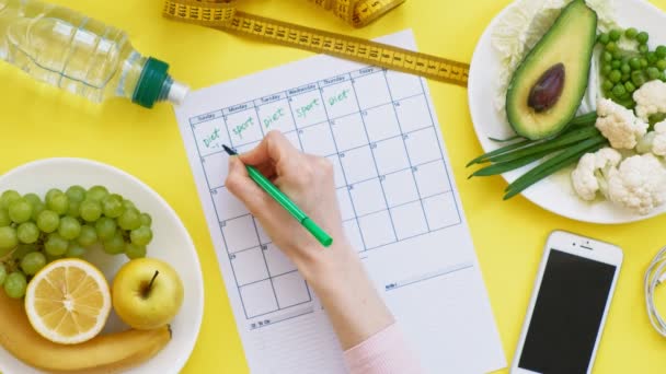 Mantenere un calendario fitness. Concetto di cibo sano, dieta, vista dall'alto, sfondo giallo — Video Stock