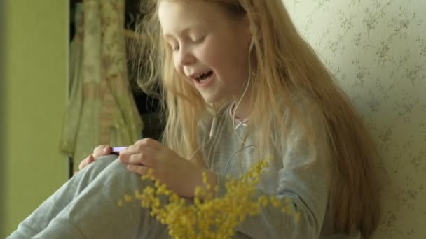 Little girl sitting on the window uses the phone — Stock Video