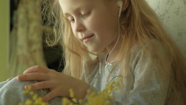 Kleines Mädchen, das am Fenster sitzt, benutzt das Telefon — Stockvideo