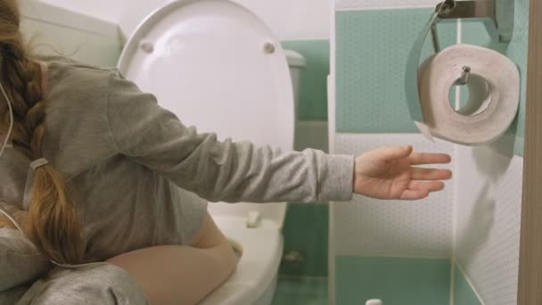 Petite fille s'assoit sur les toilettes et utilise le téléphone — Video