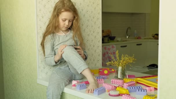 Menina sentada na janela usa o telefone — Vídeo de Stock