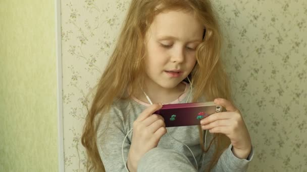 Klein meisje zittend op het raam maakt gebruik van de telefoon — Stockvideo