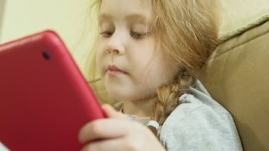  küçük kız bir bilgisayar tabletkullanarak katta oturan