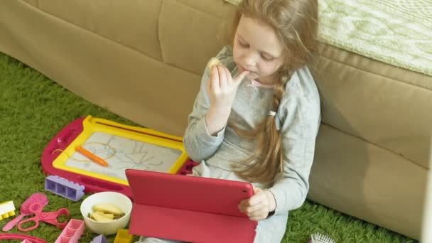 Little girl uses a computer tablet in the interior — Stock Video