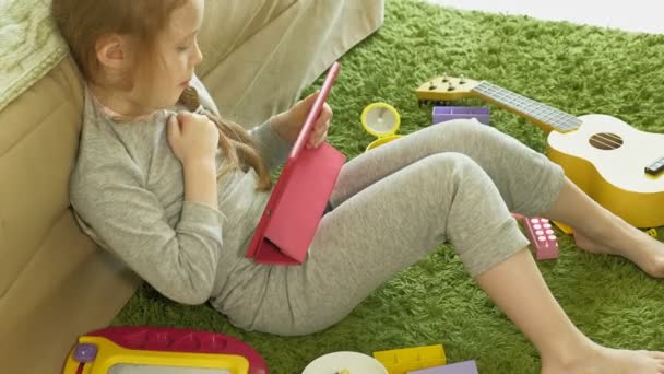 Little girl uses a computer tablet in the interior — Stock Video