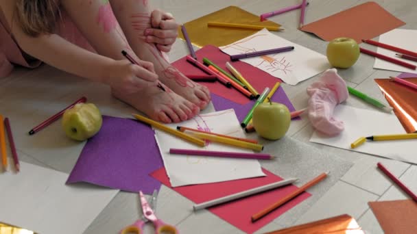 Klein meisje trekt op haar voeten met vilt-Tip pennen, Childrens creativiteit, ontwikkeling — Stockvideo