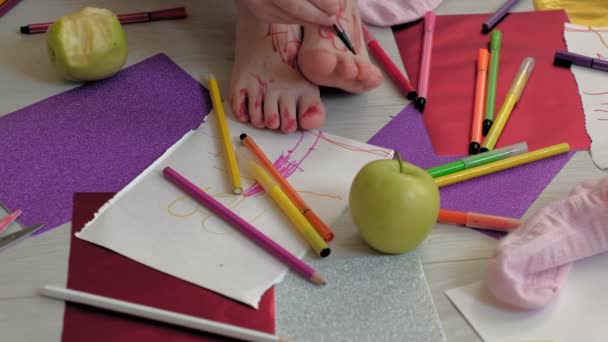 Маленька дівчинка малює на ногах з повстяними ручками, дитячою творчістю, розвитком — стокове відео