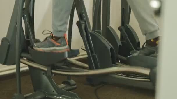 Hombre con máquina elíptica en el gimnasio . — Vídeo de stock