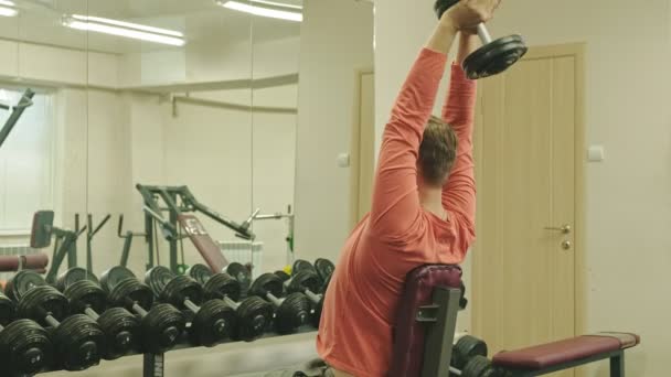 Mann macht Bankdrücken mit Kurzhanteln im Fitnessstudio — Stockvideo