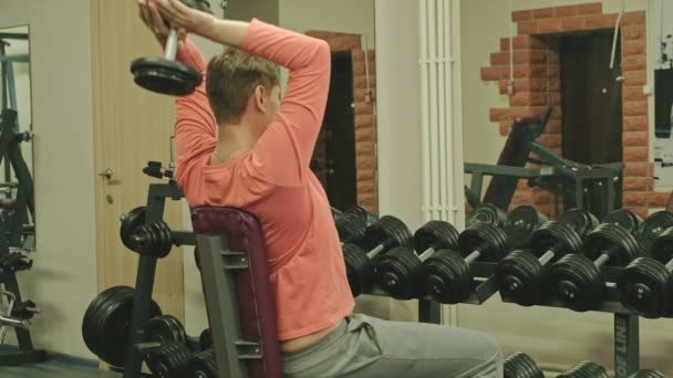 Adam fitness stüdyosunda dumbbells ile tezgah basın yapıyor — Stok video