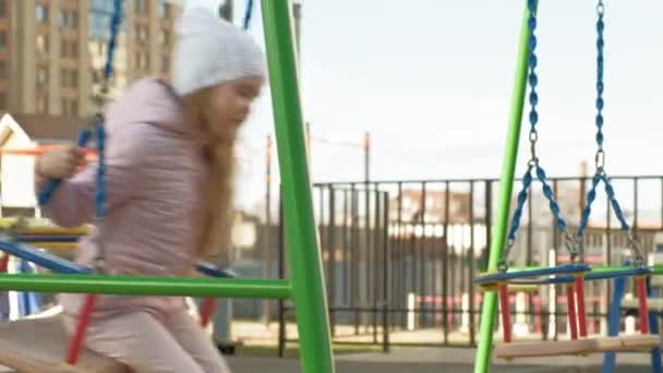 Маленька дівчинка катається на гойдалці, весна — стокове відео