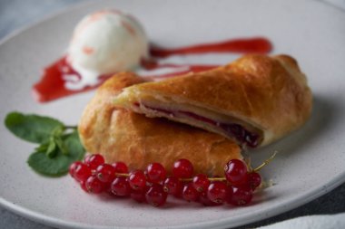 Dilimlenmiş ev yapımı berry strudel taze kırmızı kuş üzümü meyveleri ile hizmet ve pudra şekeri ile dondurma bir plaka üzerinde eski bir arka plan üzerinde