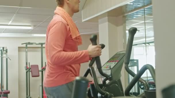 Man med elliptisk maskin i gymmet. — Stockvideo