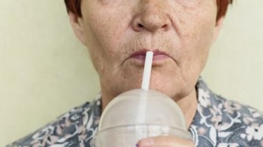 yaşlı kadın bir saman closeup bir içki içme