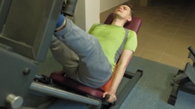 Spor salonunda simülatörde bacak presleri yapan aşırı kilolu bir adam. Fitness eğitimi. Sağlıklı yaşam tarzı kavramı