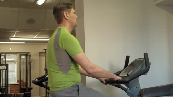 Άνθρωπος στο ποδήλατο γυμναστικής στο γυμναστήριο. Έννοια του υγιεινού τρόπου ζωής — Αρχείο Βίντεο