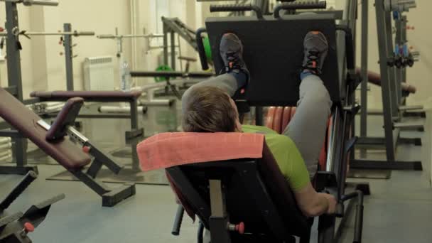 Человек с избыточным весом нажимает на симулятор в спортзале. Фитнес-тренировки. Понятие здорового образа жизни — стоковое видео
