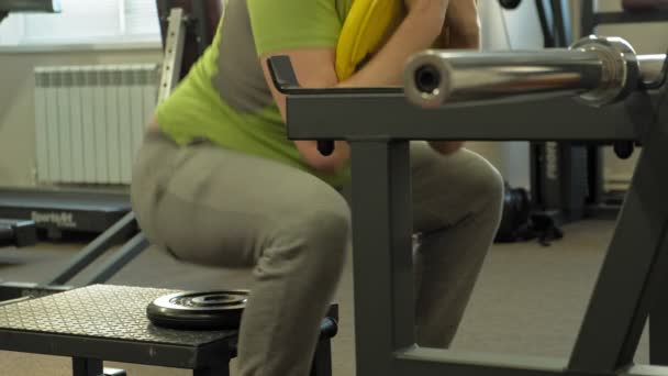 Человек с избыточным весом делает приседания с приседаниями с диском для штанги. Фитнес-тренировки. Понятие здорового образа жизни — стоковое видео