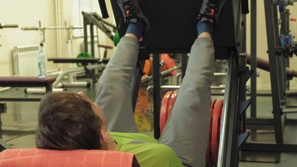 Un hombre con exceso de peso hace presión en la pierna del simulador en el gimnasio. Entrenamiento físico. concepto de estilo de vida saludable — Vídeos de Stock