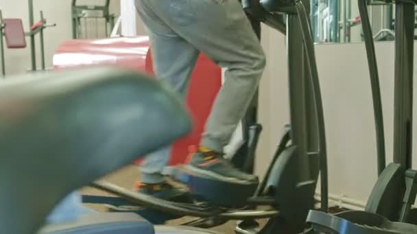 Hombre con máquina elíptica en el gimnasio . — Vídeo de stock