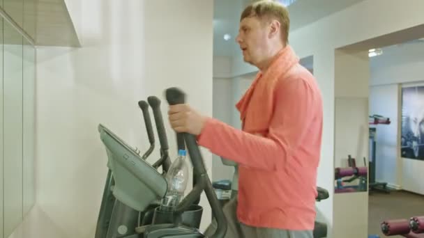 Muž s eliptickým strojem v tělocvičně. — Stock video