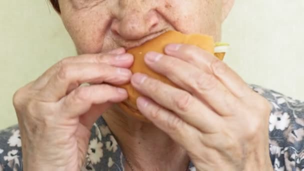 Wanita tua makan burger closeup, makanan cepat saji — Stok Video