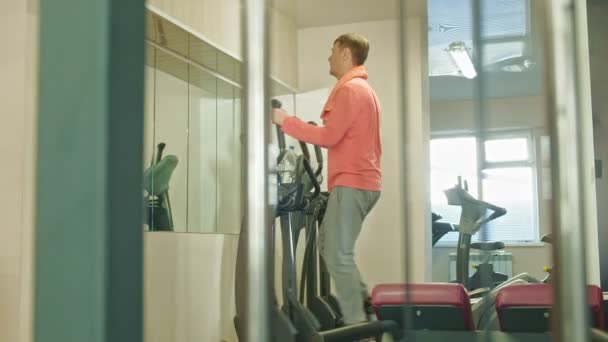Człowiek z eliptyczną maszyną w siłowni. — Wideo stockowe