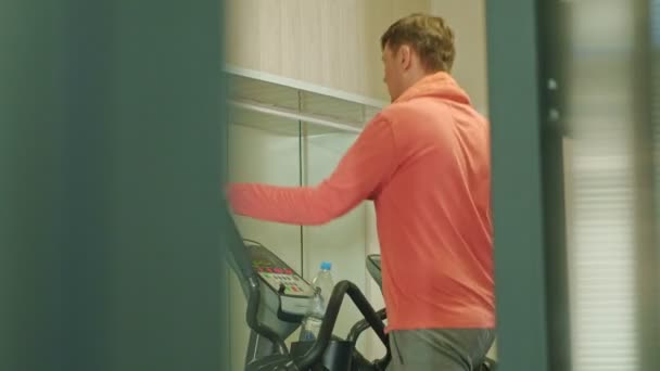 Man med elliptisk maskin i gymmet. — Stockvideo