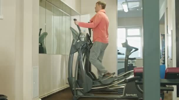 Man med elliptisk maskin i gymmet. — Stockvideo