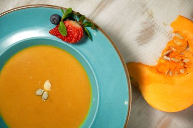 Kabak çekirdeği ile mavi bir tabakta kabak çorbası püresi. Açık ahşap arka plan.