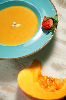 Kabak çekirdeği ile mavi bir tabakta kabak çorbası püresi. Açık ahşap arka plan.