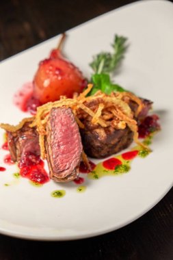 Beyaz tabakta armutlu et libiftek. Koyu ahşap arka plan. Restoran yemekleri.