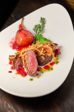 Beyaz tabakta armutlu et libiftek. Koyu ahşap arka plan. Restoran yemekleri.