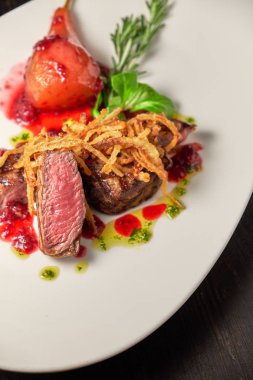 Beyaz tabakta armutlu et libiftek. Koyu ahşap arka plan. Restoran yemekleri.