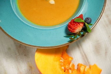 Kabak çekirdeği ile mavi bir tabakta kabak çorbası püresi. Açık ahşap arka plan.