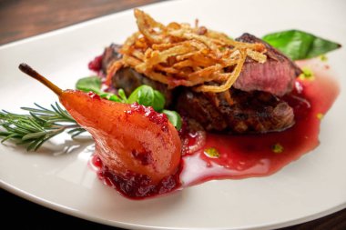 Beyaz tabakta armutlu et libiftek. Koyu ahşap arka plan. Restoran yemekleri.