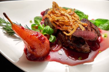 Beyaz tabakta armutlu et libiftek. Koyu ahşap arka plan. Restoran yemekleri.