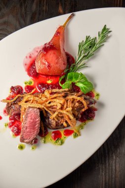 Beyaz tabakta armutlu et libiftek. Koyu ahşap arka plan. Restoran yemekleri.