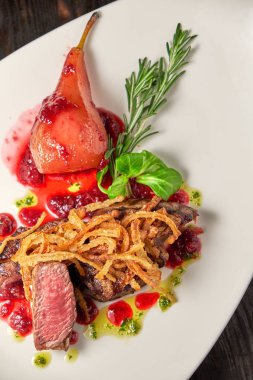 Beyaz tabakta armutlu et libiftek. Koyu ahşap arka plan. Restoran yemekleri.