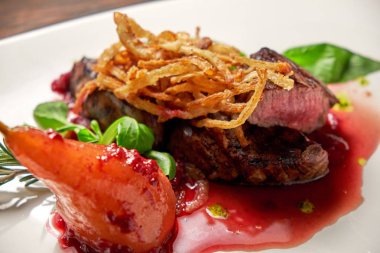 Beyaz tabakta armutlu et libiftek. Koyu ahşap arka plan. Restoran yemekleri.