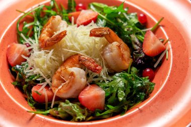 Taze arugula salatası, karides ve çilek. Koyu ahşap arka plan. Restoran menüsü