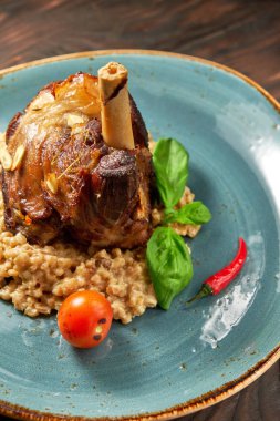 Mavi bir tabak üzerinde bir garnitür ile Knuckle et çanak. Koyu ahşap arka plan.