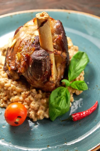 Mavi bir tabak üzerinde bir garnitür ile Knuckle et çanak. Koyu ahşap arka plan.