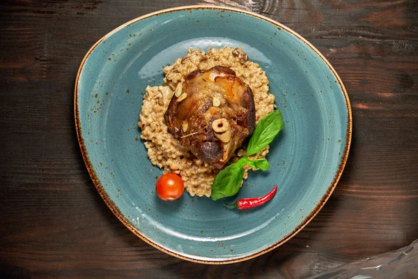 Mavi bir tabak üzerinde bir garnitür ile Knuckle et çanak. Koyu ahşap arka plan.