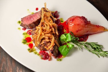 Beyaz tabakta armutlu et libiftek. Koyu ahşap arka plan. Restoran yemekleri.