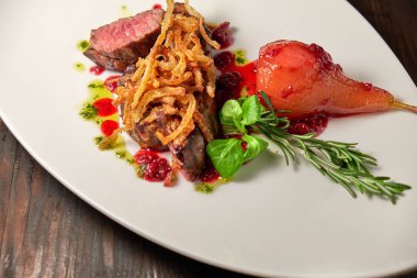 Beyaz tabakta armutlu et libiftek. Koyu ahşap arka plan. Restoran yemekleri.