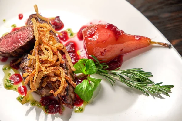 Beyaz tabakta armutlu et libiftek. Koyu ahşap arka plan. Restoran yemekleri.