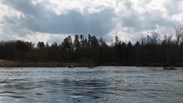 Emberek evezni a folyó mentén felhős időben. — Stock videók