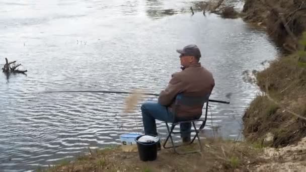 Homem maduro pega peixe no rio . — Vídeo de Stock